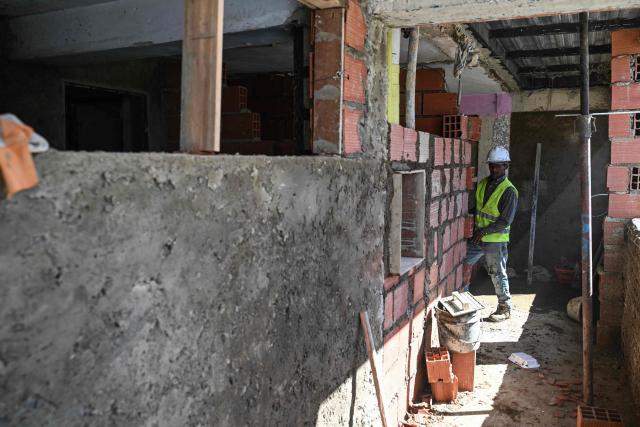 A worker rebuilds a building damaged during the US military intervention in Venezuela, located in Catia La Mar, La Guaira state, on January 18, 2026. (Photo by Ronaldo SCHEMIDT / AFP)