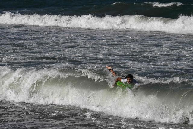 A man surfs near the beach in La Guaira, Venezuela on January 18, 2026. (Photo by Ronaldo SCHEMIDT / AFP)