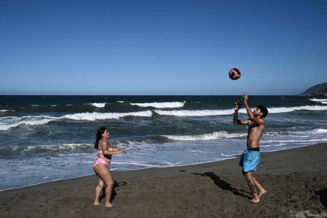 People play with a ball at the beach in La Guaira, Venezuela on January 18, 2026. (Photo by Ronaldo SCHEMIDT / AFP)