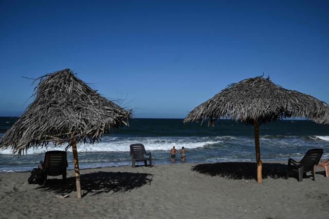 People hang out at the beach in La Guaira, Venezuela on January 18, 2026. (Photo by Ronaldo SCHEMIDT / AFP)