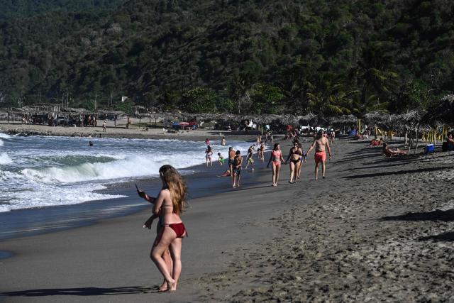 People hang out at the beach in La Guaira, Venezuela on January 18, 2026. (Photo by Ronaldo SCHEMIDT / AFP)