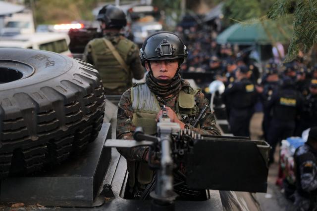 A Guatemalan soldier in an armored vehicle guards the entrance to the men's Preventive Detention Center in Guatemala City on January 18, 2026. Guatemala's government accused gang members of killing eight police officers in several attacks on January 18, 2025, after refusing to negotiate the transfer of leaders of these dangerous gangs to a lower-security prison. The killings occurred a day after gang-affiliated inmates took 46 people hostage in three prisons across the country. Police regained control of one of the prisons. (Photo by Edwin BERCIAN / AFP)