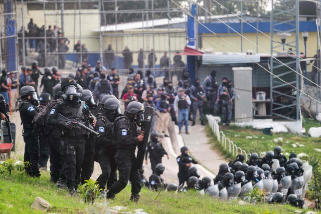 Guatemalan riot police officers guard the entrance to the men's Preventive Detention Center in Guatemala City on January 18, 2026. Guatemala's government accused gang members of killing eight police officers in several attacks on January 18, 2025, after refusing to negotiate the transfer of leaders of these dangerous gangs to a lower-security prison. The killings occurred a day after gang-affiliated inmates took 46 people hostage in three prisons across the country. Police regained control of one of the prisons. (Photo by Edwin BERCIAN / AFP)