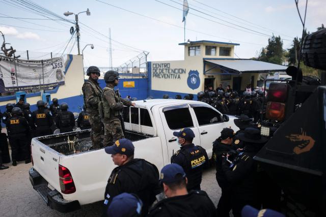 Guatemalan soldiers and police officers guard the entrance to the men's Preventive Detention Center in Guatemala City on January 18, 2026. Guatemala's government accused gang members of killing eight police officers in several attacks on January 18, 2025, after refusing to negotiate the transfer of leaders of these dangerous gangs to a lower-security prison. The killings occurred a day after gang-affiliated inmates took 46 people hostage in three prisons across the country. Police regained control of one of the prisons. (Photo by Edwin Bercian / AFP)