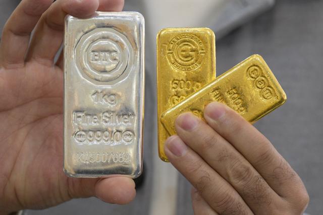 (FILES) A jeweller shows gold and silver bars at his shop in downtown Kuwait City on January 12, 2026. Gold and silver prices hit record highs on January 12 after US President Donald Trump threatened to hit several top European countries with tariffs over their opposition to the US takeover of Greenland, sparking fresh trade war fears. (Photo by YASSER AL-ZAYYAT / AFP)