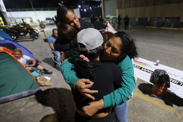 People hug each other during a vigil to demand the freedom of Venezuelan political prisoners near Zona 7 prison in Caracas on January 18, 2026. (Photo by Pedro MATTEY / AFP)