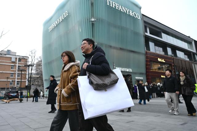 People walk out from a mall in Beijing on January 18, 2026. (Photo by WANG Zhao / AFP)