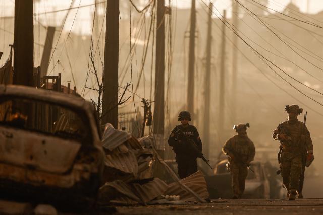Chilean soldiers patrol among the damage after a wildfire in Concepcion, Chile on January 18, 2026. Uncontrolled wildfires tore through communities in southern Chile, leaving charred ruins in their wake and at least 19 dead, authorities said on January 18, 2026. (Photo by Raul BRAVO / AFP)