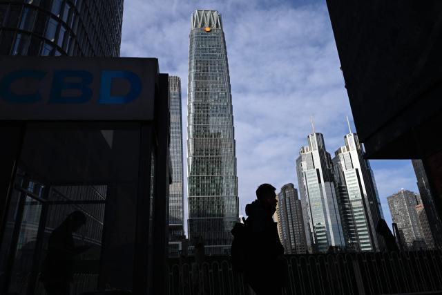 A commuter walks at the Central Business District (CBD) in Beijing on January 19, 2026. (Photo by WANG Zhao / AFP)