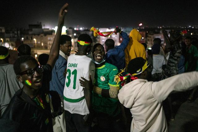 Senegal supporters embrace as they celebrate at a fan zone at the African Renaissance Monument in Dakar on January 18, 2026 after watching Senegal defeat Morocco in the Africa Cup of Nations (CAN) final football match being played in Rabat, Morocco. (Photo by Carmen Abd Ali / AFP)