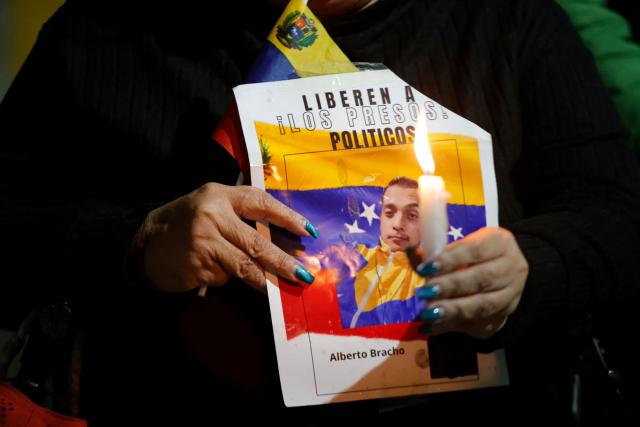 A woman shows a sign during a vigil to demand the freedom of Venezuelan political prisoners near Zona 7 prison in Caracas on January 18, 2026. (Photo by Pedro MATTEY / AFP)