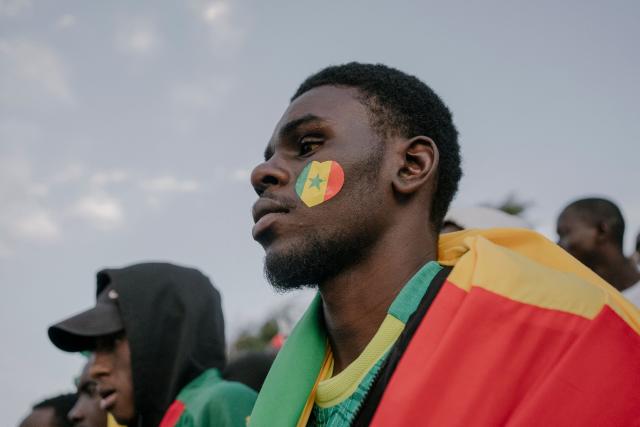 A Senegal football fan wears a sticker on his cheek in the colors of the Senegal flag at the African Renaissance Monument in Dakar on January 18, 2026 as supporters gather at a fan zone to watch the Africa Cup of Nations (CAN) final football match between Senegal and Morocco played in Rabat, Morocco. (Photo by Carmen Abd Ali / AFP)