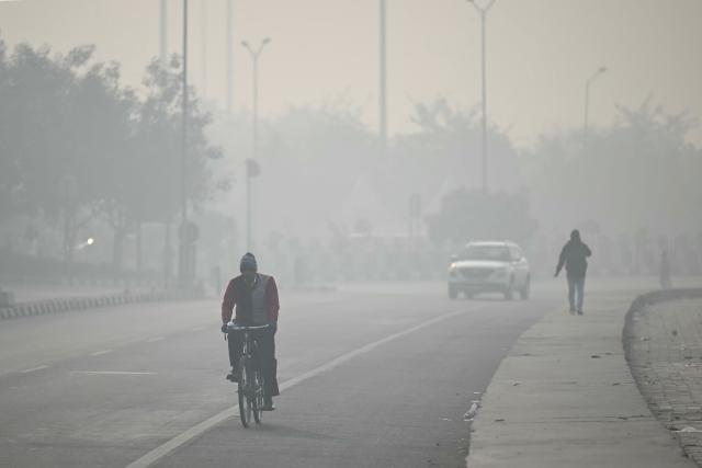 Commuters ride along a street amid dense smog in New Delhi on January 19, 2026. (Photo by Sajjad HUSSAIN / AFP)
