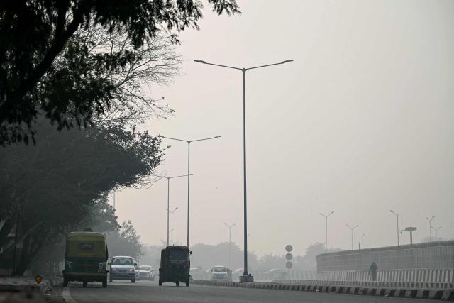 Commuters ride along a street amid dense smog in New Delhi on January 19, 2026. (Photo by Sajjad HUSSAIN / AFP)
