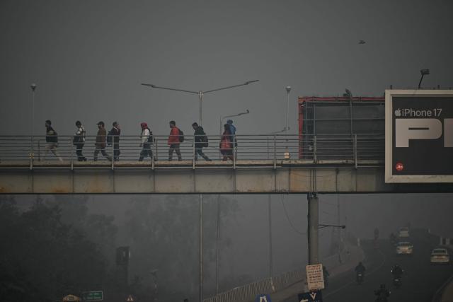 People walk across an overbridge amid dense smog in New Delhi on January 19, 2026. (Photo by Sajjad HUSSAIN / AFP)