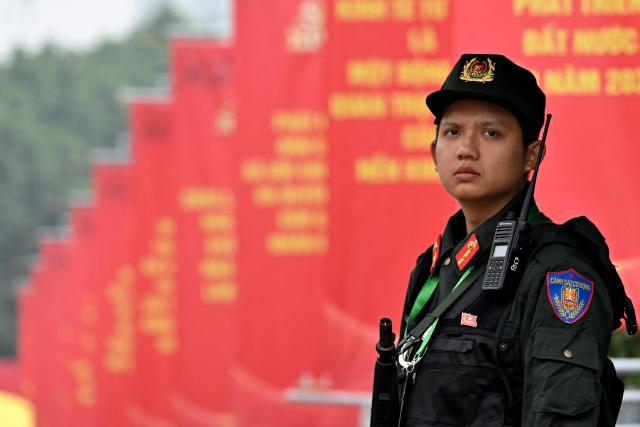 A police officer stands in front of posters for the 14th Congress of the Communist Party of Vietnam outside the National Convention Center in Hanoi on January 19, 2026. Vietnam's ruling Communist Party convened on January 19 to begin their twice-a-decade congress, where leader To Lam is looking to tighten his grip on power less than two years after assuming the top role. (Photo by Nhac NGUYEN / AFP)