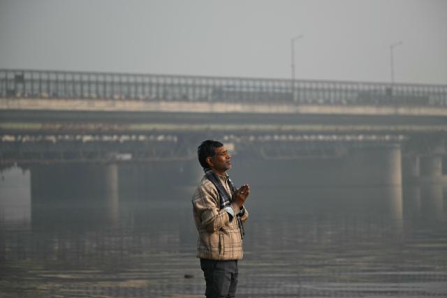 A man offers prayers along the banks of river Yamuna amid dense smog in New Delhi on January 19, 2026. (Photo by Sajjad HUSSAIN / AFP)