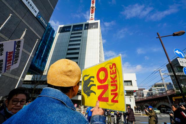 A participant taking part in a demonstration against the restart of the Kashiwazaki-Kariwa Nuclear Power Plant holds up a sign reading "No Nukes" in front of Tokyo Electric Power Company's headquarters in Tokyo on January 19, 2026. (Photo by Kazuhiro NOGI / AFP)