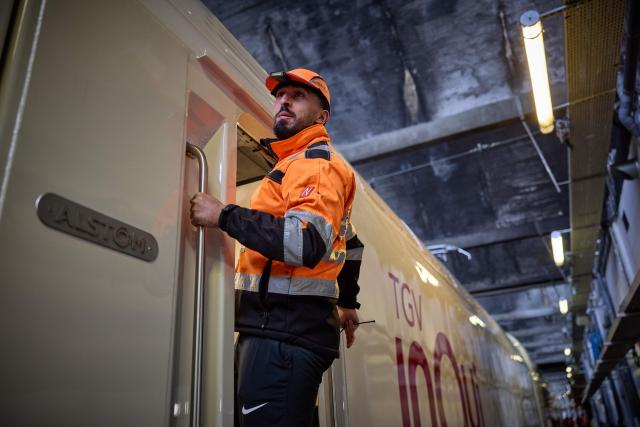 (FILES) An SNCF engineer hangs out of the cockpit of the new TGV INOUI train as it is prepared for it's unvailing at a technical centre of the French national rail company SNCF in Paris, on March 10, 2025. French railway company SNCF Voyageurs orders 15 new TGV trains from Alstom, worth approximately Ђ600 million. (Photo by Kiran RIDLEY / AFP)