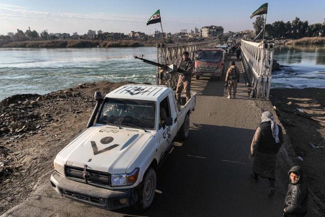 People cross the bridge between the eastern and western banks of the Euphrates River in the province of Deir Ezzor, eastern Syria on January 19, 2026, as Syrian security forces move toward the east of the Euphrates after an agreement was reached on January 18,  between the Syrian government and the Kurds. Syria's army on January 19, deployed its forces in parts of the eastern Deir Ezzor province formerly controlled by Kurdish forces following their withdrawal from the area. After two days of rapid gains in Kurdish-controlled territory, Syrian President announced on January 18, a deal with their that includes a ceasefire and the integration of the Kurdish administration and forces into the central state. (Photo by OMAR HAJ KADOUR / AFP)