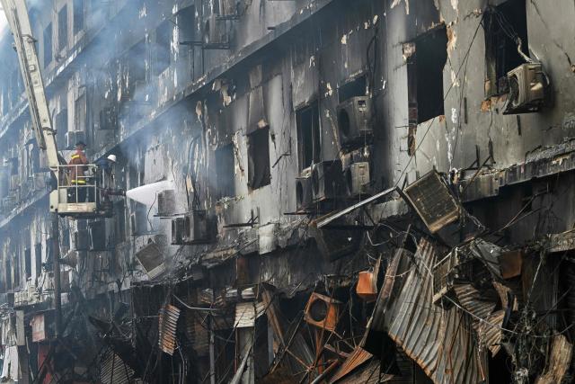 Fire fighters perform a cooling operation on a burnt structure after a massive fire at a shopping mall in Karachi on January 19, 2026. (Photo by Asif HASSAN / AFP)