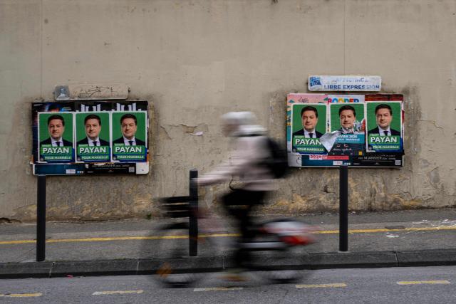 A man rides a bicycle past municipal electoral posters of Marseille's Mayor Benoit Payan, a candidate for the upcoming municipal elections, in downtown Marseille on January 19, 2026. (Photo by MIGUEL MEDINA / AFP)