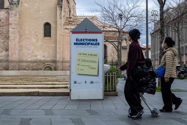 Pedestrians walk past a poster inviting citizens to vote for the upcoming municipal elections, in downtown Marseille on January 19, 2026. (Photo by MIGUEL MEDINA / AFP)