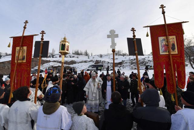 An Orthodox priest blesses the icy waters of Kara-Balta River during the Epiphany holiday near the village of Sosnovka, northern Kyrgyzstan on January 19, 2026. (Photo by Vyacheslav OSELEDKO / AFP)