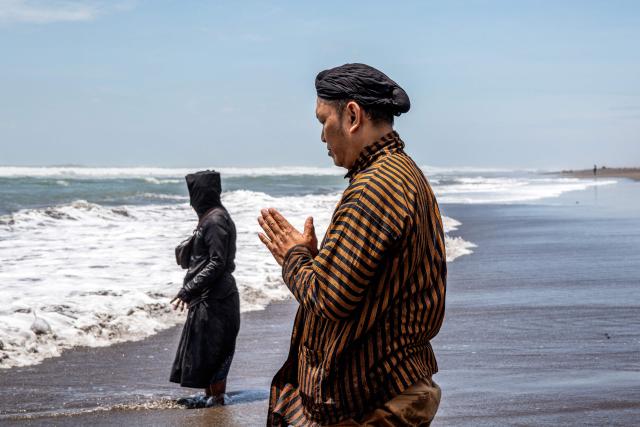 Palace attendants known as abdi dalem pray during the 'Labuhan Laut' ritual of the Yogyakarta Palace, expressing gratitude for the sea's blessings by casting offerings into the ocean at the Parangkusumo Beach in Bantul, Yogyakarta on January 19, 2026. (Photo by DEVI RAHMAN / AFP)