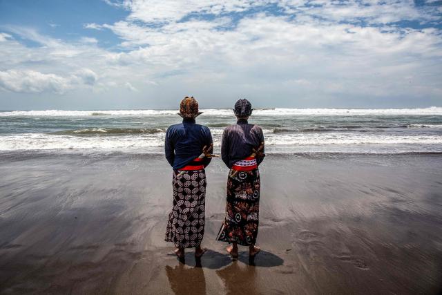 TOPSHOT - Palace attendants known as abdi dalem pray during the 'Labuhan Laut' ritual of the Yogyakarta Palace, expressing gratitude for the sea's blessings by casting offerings into the ocean at the Parangkusumo Beach in Bantul, Yogyakarta on January 19, 2026. (Photo by DEVI RAHMAN / AFP)