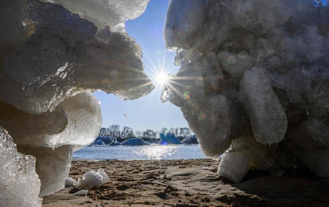 The sun is seen through large chunks of ice washed up along the banks of the Elbe river near Geesthacht, northern Germany, on January 19, 2026. Following several days of freezing winter temperatures and a low water level, ground ice started to form and to emerge to the surface. (Photo by DANIEL REINHARDT / AFP)