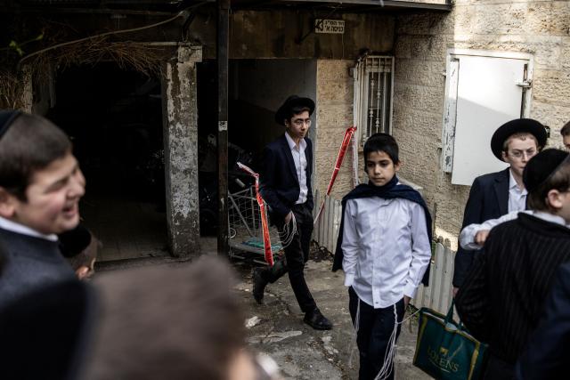 Ultra-orthodox Jewish boys gather at the site where faulty heating system left two babies dead and many others injured at a day care in Jerusalem on January 19, 2026. Israeli doctors declared two babies dead after medics evacuated 55 children from a daycare centre in Jerusalem on January 19, with local media reporting the incident may have been linked to the facility's heating system. (Photo by JOHN WESSELS / AFP)