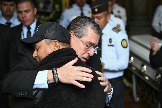 Guatemalas President Bernardo Arevalo hugs a relative of a slain officer during a funeral ceremony at the Interior Ministry headquarters in Guatemala City on July 19, 2026. Guatemala's president on July 18 declared a 30-day nationwide state of emergency to combat criminal gangs after authorities accused the groups of killing eight police officers and holding hostages at three prisons. The killings occurred in the Guatemalan capital and surrounding areas a day after gang-affiliated inmates took 46 people hostage in the three prisons across the country to demand incarcerated gang leaders be moved to lower-security facilities. (Photo by JOHAN ORDONEZ / AFP)