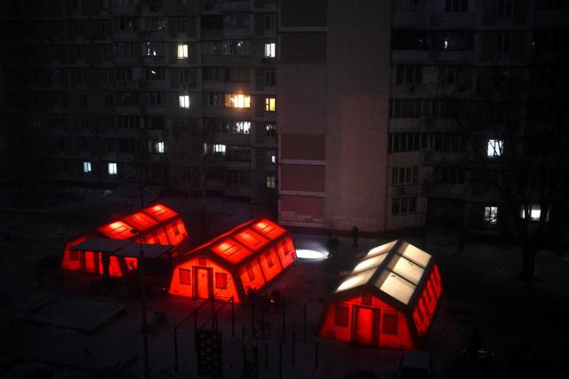 Local residents using flashlights walk past tents with heating set up in the courtyard of a residential building in Kyiv on January 19, 2026, amid the Russian invasion of Ukraine. Russian attacks have left Ukraine's energy grid teetering on the brink of collapse and have disrupted power and water supplies to millions over recent weeks. (Photo by Sergei GAPON / AFP)