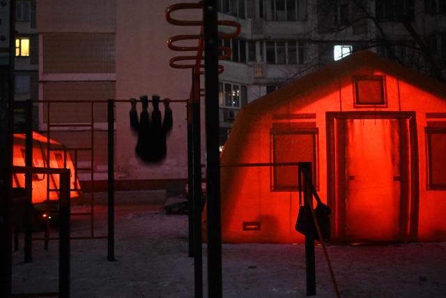 A man exercises at an outdoor sports ground next to tents with heating set up in the courtyard of a residential building in Kyiv on January 19, 2026, amid the Russian invasion of Ukraine. Russian attacks have left Ukraine's energy grid teetering on the brink of collapse and have disrupted power and water supplies to millions over recent weeks. (Photo by Sergei GAPON / AFP)