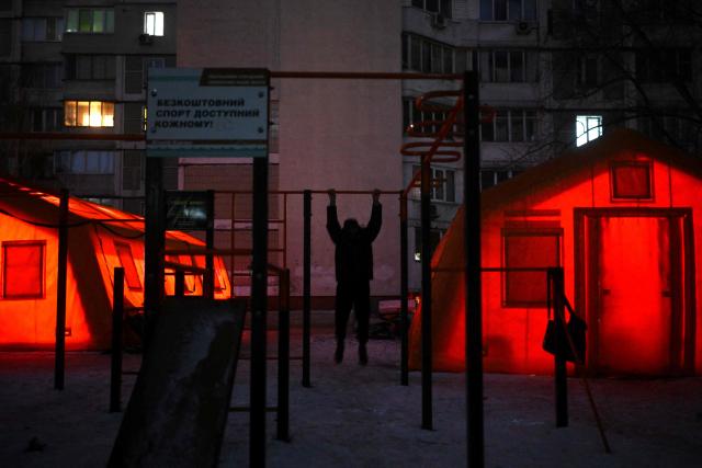 A man exercises at an outdoor sports ground next to tents with heating set up in the courtyard of a residential building in Kyiv on January 19, 2026, amid the Russian invasion of Ukraine. Russian attacks have left Ukraine's energy grid teetering on the brink of collapse and have disrupted power and water supplies to millions over recent weeks. (Photo by Sergei GAPON / AFP)