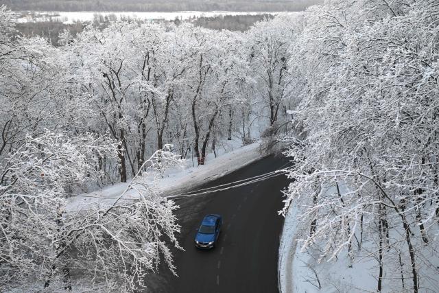 A car drives along a snowy landscape in Kyiv on January 19, 2026, amid the Russian invasion of Ukraine. (Photo by Sergei GAPON / AFP)