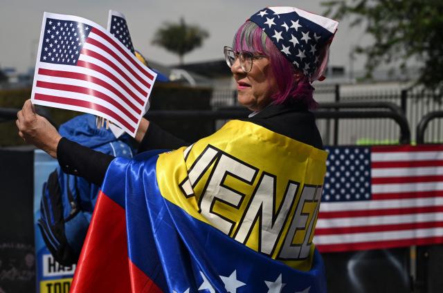 A woman wearing a Venezuelan flag holds US flags as members of the Venezuelan diaspora gather to call for the release of political prisoners outside the US embassy in Bogota on January 19, 2026.  (Photo by Raul ARBOLEDA / AFP)