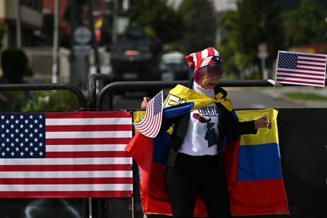 A woman wearing a Venezuelan flag holds US flags as members of the Venezuelan diaspora gather to call for the release of political prisoners outside the US embassy in Bogota on January 19, 2026.  (Photo by Raul ARBOLEDA / AFP)