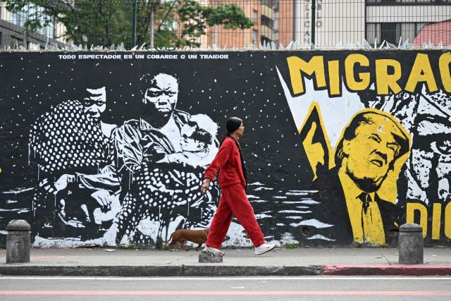 A woman walks past anti-immigration-policy graffiti depicting US President Donald Trump in Bogota on January 18, 2026.  (Photo by Raul ARBOLEDA / AFP)