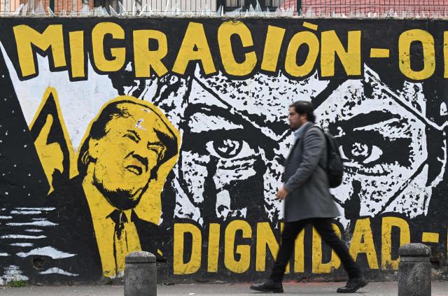A man walks past an anti-immigration-policy graffiti depicting US President Donald Trump in Bogota on January 18, 2026.  (Photo by Raul ARBOLEDA / AFP)