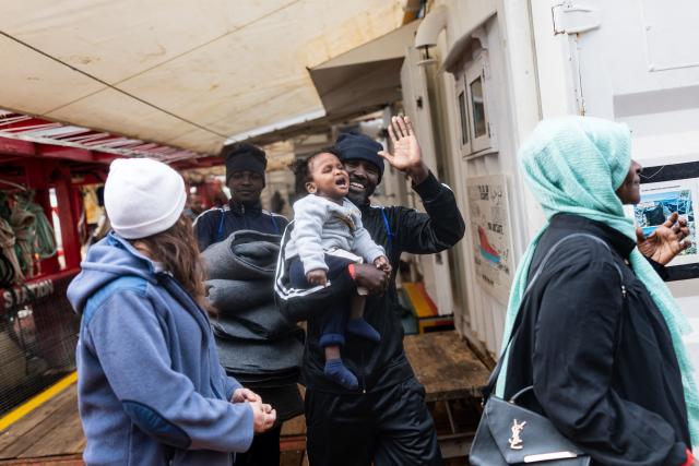 Rescued Migrants bid farewell to crew members of the rescue ship "Ocean Viking" operated by the NGO SOS Mediterranee, as they disembark at the port of Palermo, southern Italy, on January 19, 2026. The humanitarian ship Ocean Viking rescued 90 migrants in the Mediterranean Sea before docking at the port of Palermo, Italy, where they were received by port authorities and the Italian Red Cross. (Photo by Sameer Al-DOUMY / AFP)