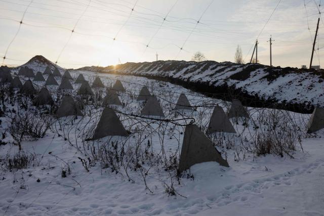 This photograph shows Dragon's Teeth (pyramidal anti-tank obstacles made from reinforced concrete) wrapped in barbed wire in a field at an undisclosed location in eastern Ukraine on January 19, 2026, amid the Russian invasion of Ukraine. (Photo by Tetiana DZHAFAROVA / AFP)