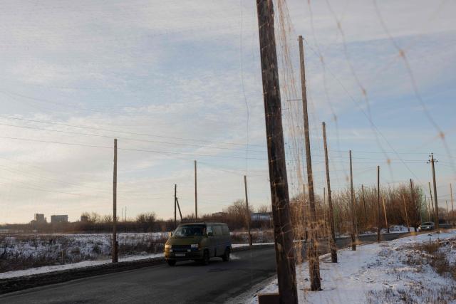 This photograph shows vehicles driving down a road covered with anti-drone netting to protect against drone attacks, at an undisclosed location in eastern Ukraine, on January 19, 2026, amid the Russian invasion of Ukraine. (Photo by Tetiana DZHAFAROVA / AFP)