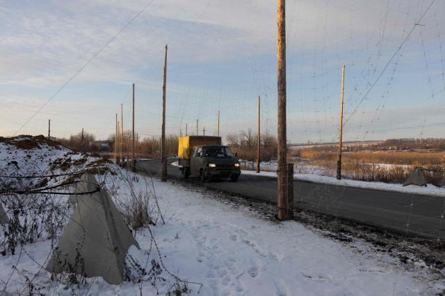 This photograph shows a van driving down a road covered with anti-drone netting to protect against drone attacks, at an undisclosed location in eastern Ukraine, on January 19, 2026, amid the Russian invasion of Ukraine. (Photo by Tetiana DZHAFAROVA / AFP)