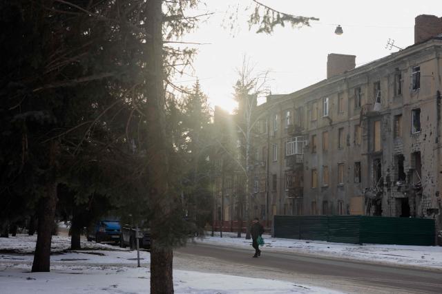A man walks down the street near a damaged residential building in Kramatorsk on January 19, 2026, amid the Russian invasion of Ukraine. (Photo by Tetiana DZHAFAROVA / AFP)