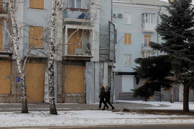 People walk next to a damaged residential building in Kramatorsk on January 19, 2026, amid the Russian invasion of Ukraine. (Photo by Tetiana DZHAFAROVA / AFP)