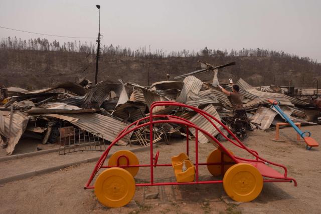 A man clears debris from a burnt home in the Gabriela Mistral neighborhood after a wildfire in Lirquen, Chile, on January 19, 2026. Wildfires that have killed 19 people in southern Chile and wiped out entire towns, raged for a third day on January 19, fanned by high temperatures and strong winds at the height of the southern hemisphere summer. (Photo by Raul BRAVO / AFP)
