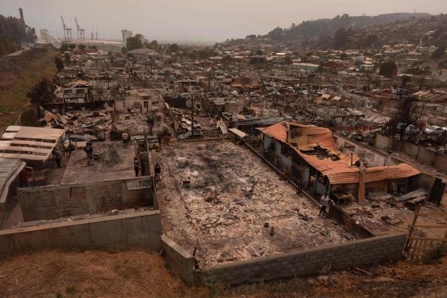 Residents of the Gabriela Mistral neighborhood clear debris from their burnt homes after a wildfire in Lirquen, Chile, on January 19, 2026. Wildfires that have killed 19 people in southern Chile and wiped out entire towns, raged for a third day on January 19, fanned by high temperatures and strong winds at the height of the southern hemisphere summer. (Photo by Raul BRAVO / AFP)