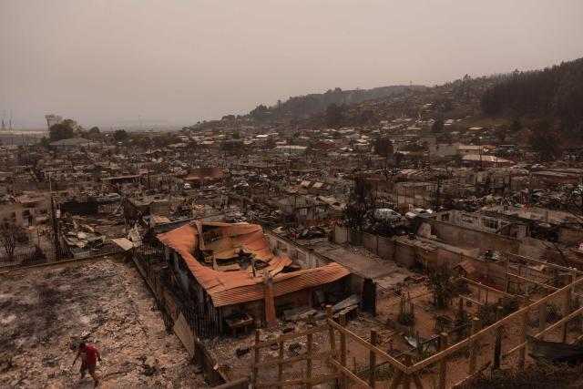 Residents of the Gabriela Mistral neighborhood clear debris from their burnt homes after a wildfire in Lirquen, Chile, on January 19, 2026. Wildfires that have killed 19 people in southern Chile and wiped out entire towns, raged for a third day on January 19, fanned by high temperatures and strong winds at the height of the southern hemisphere summer. (Photo by Raul BRAVO / AFP)